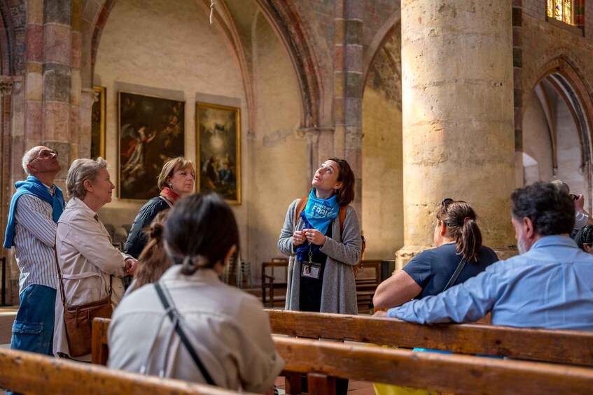 A group of people inside a church with stone columns and paintings on the walls. 4