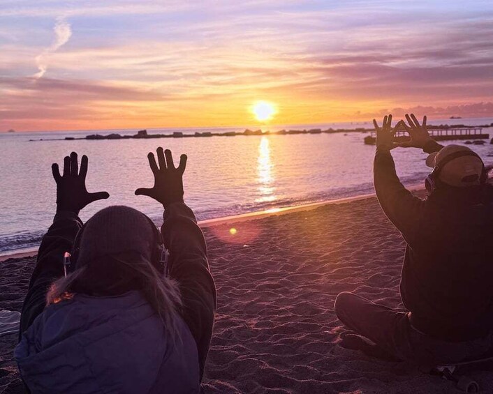 Two people sitting on a beach facing the sunset. 5