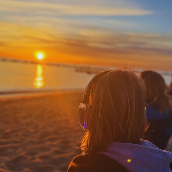 A sunset over a beach with people wearing headphones. 2