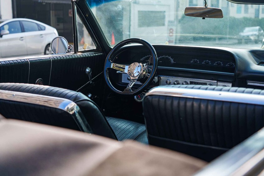 A vintage car interior with a steering wheel, dashboard, and leather seats. 2