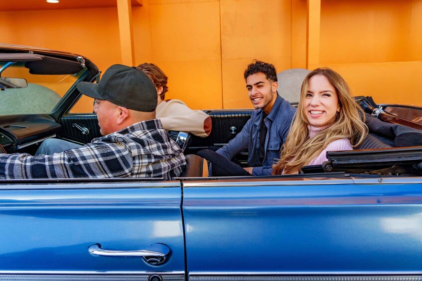 A blue convertible car with four people inside. 5