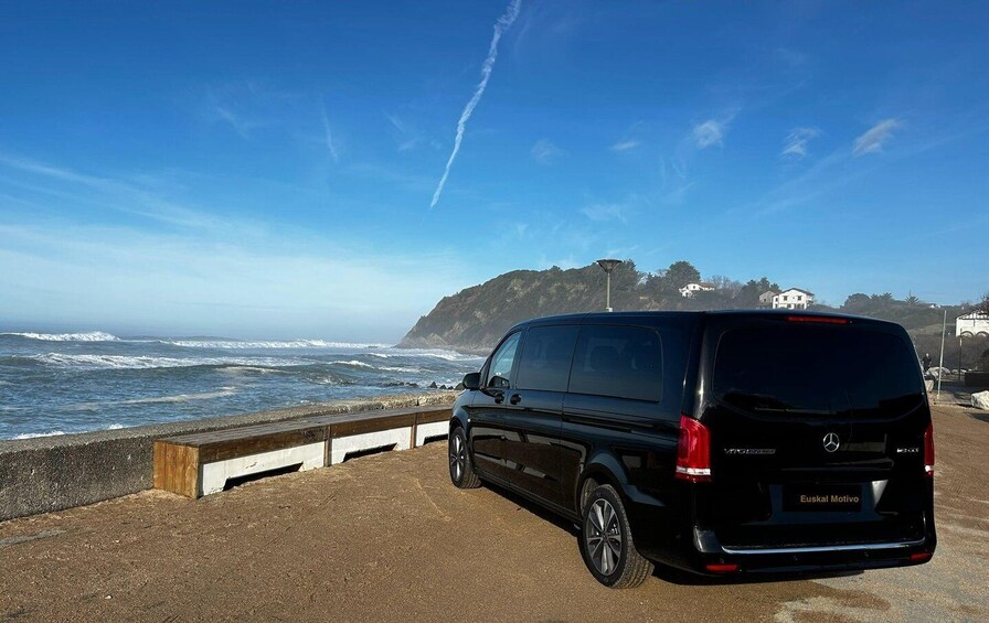 A black van parked by the seaside with waves crashing in the background. 3