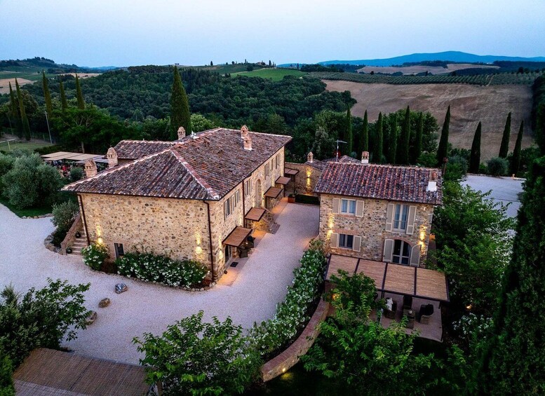 A stone house with a tiled roof surrounded by lush greenery and rolling hills in the background. 5