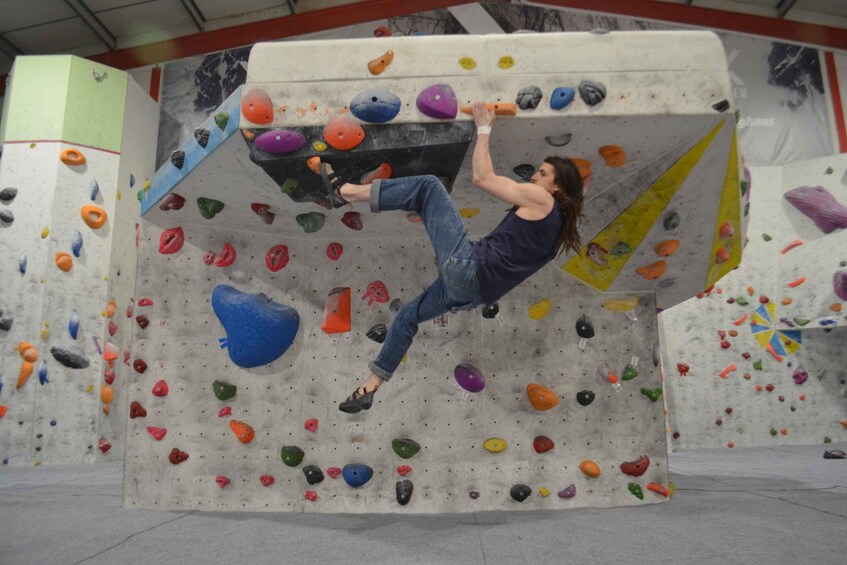 A person climbing a rock wall with various colored holds. 3