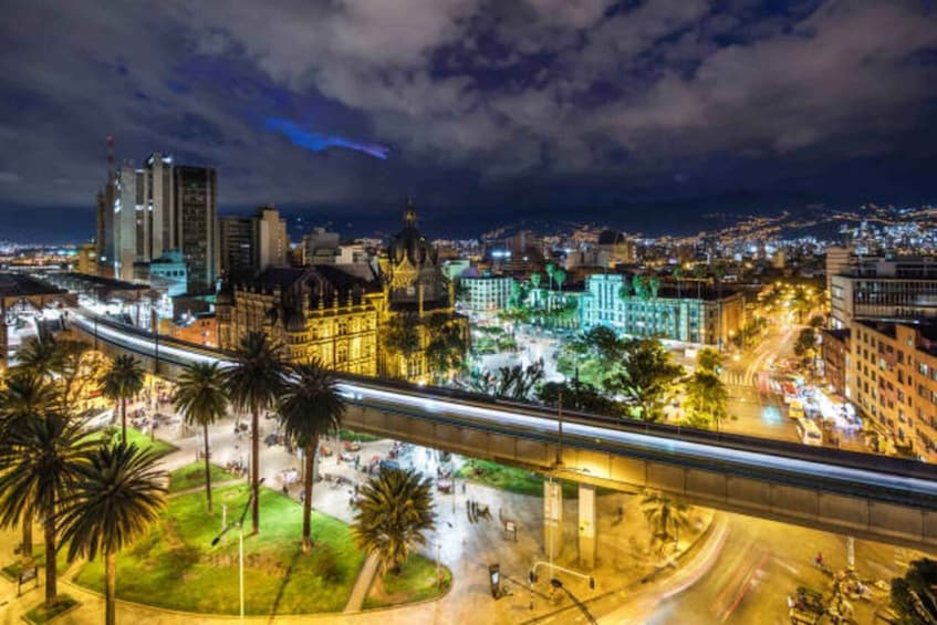 A cityscape at night with illuminated buildings, a bridge, and palm trees. 1