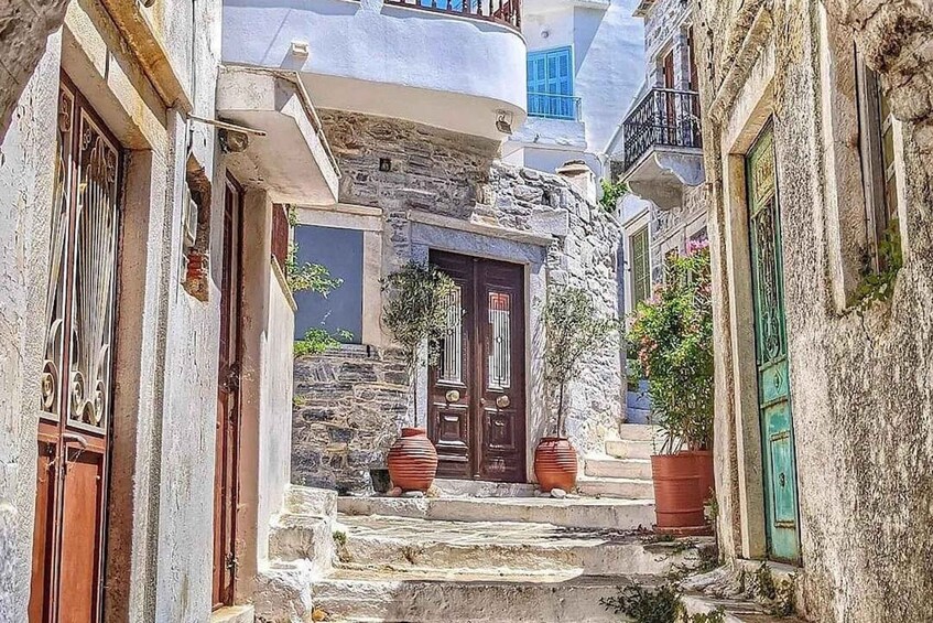 A narrow street with stone buildings, a wooden door, and potted plants. 1
