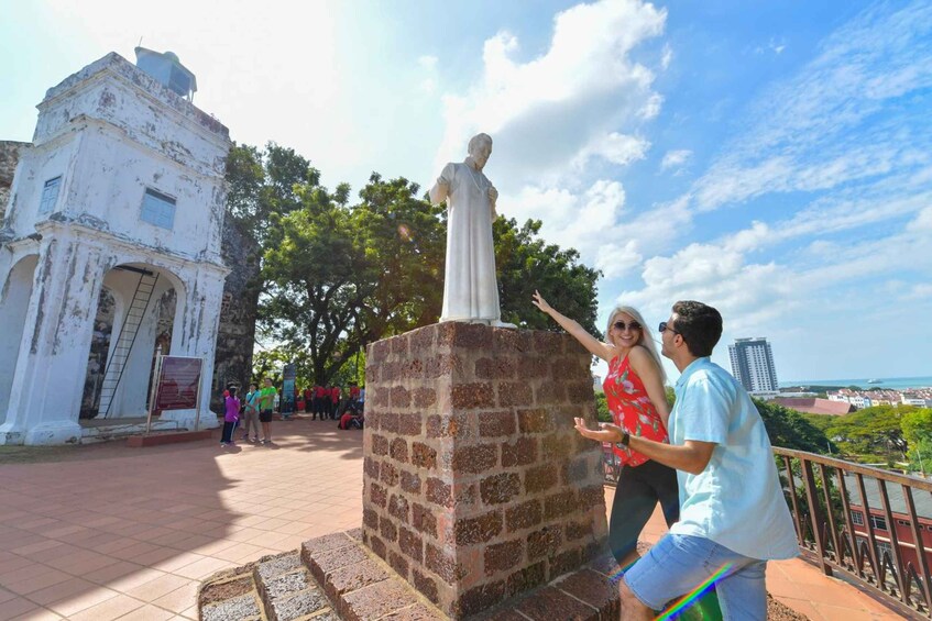 A statue on a brick pedestal, a white colonial building, and a view of the cityscape. 2