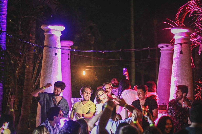A group of people at an outdoor event with illuminated pillars and string lights. 1