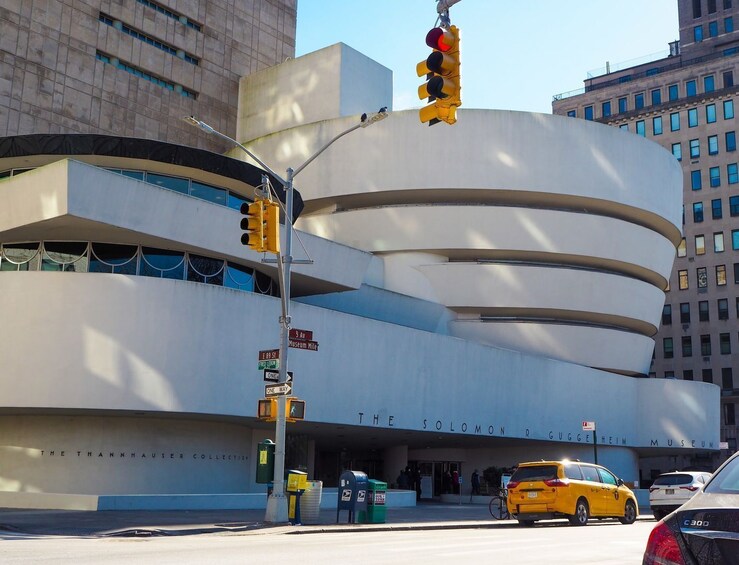 Das Solomon R. Guggenheim Museum mit modernem Design, Ampeln und einem gelben Taxi auf der Straße. 1