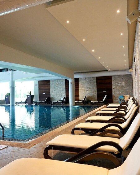 An indoor swimming pool with lounge chairs and a stone wall. 4