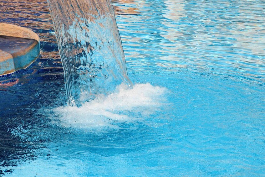 A pool with clear blue water and a rusted metal structure. 2