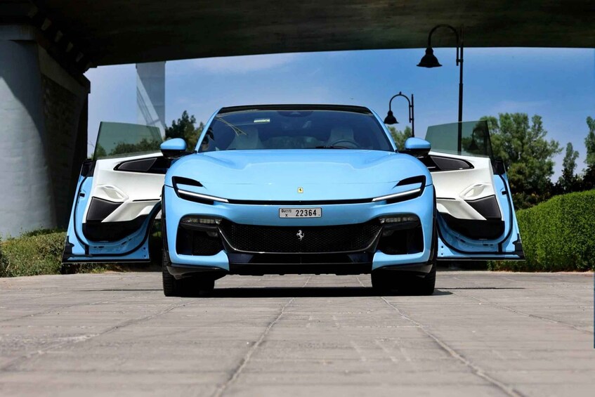A light blue sports car parked under a bridge with a clear sky in the background. 4