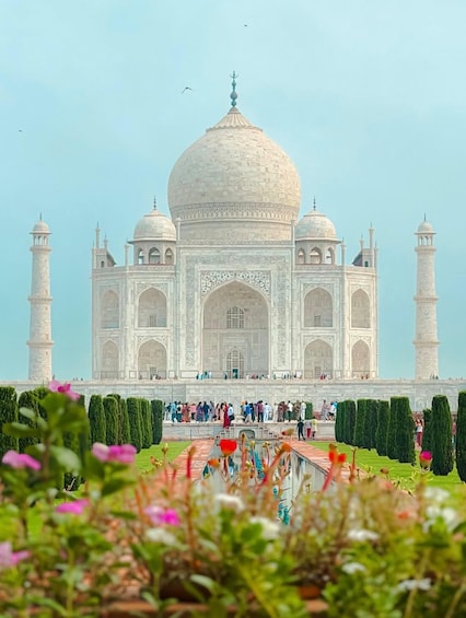 The Taj Mahal with its four minarets and central dome, surrounded by well-manicured gardens and visitors. 4