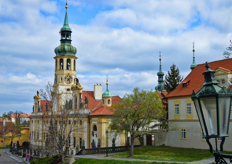 A historic building with a clock tower, a church, and a street lamp. 3