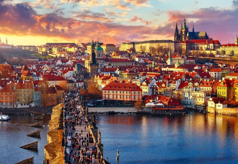 A panoramic view of a city with a prominent river, historic buildings, and a bridge with people walking. 1