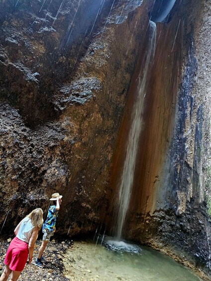 A waterfall in a rocky cave with a pool at the bottom. 3