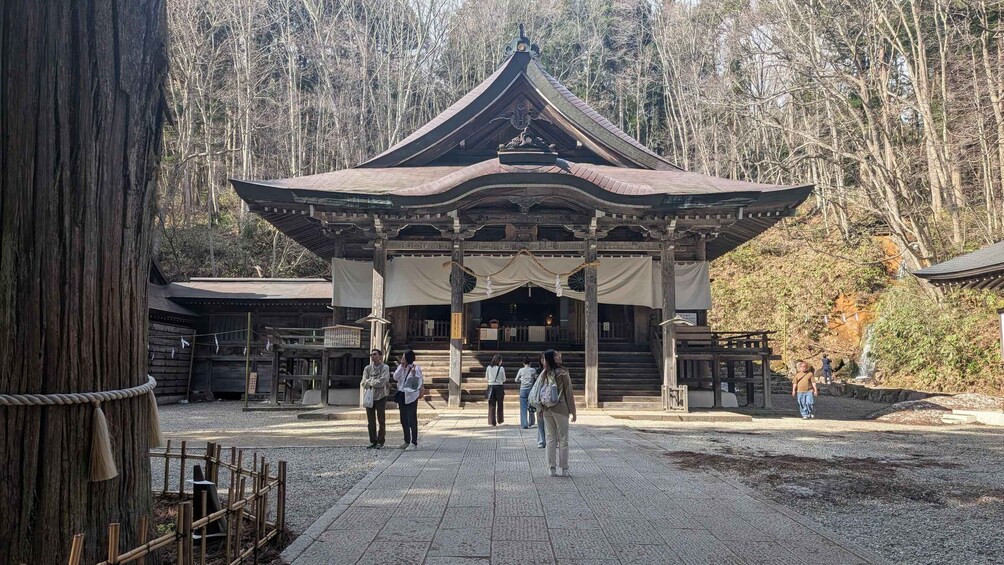 A traditional Japanese temple with a wooden structure and a thatched roof, surrounded by trees. 4