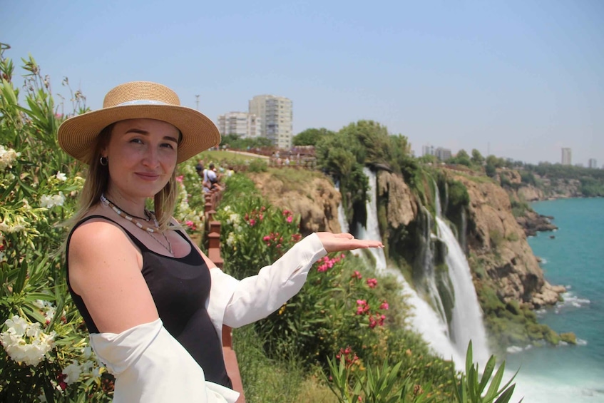 A person pointing at a waterfall with a cityscape in the background. 5