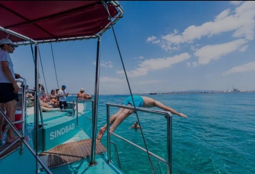 A boat with people swimming in the water, a clear sky, and a distant shoreline. 5