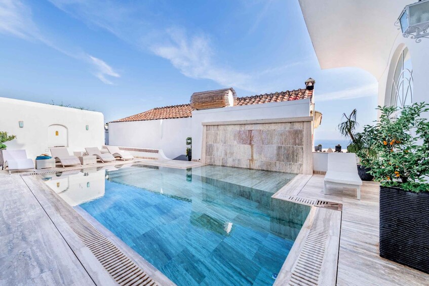 A rooftop swimming pool with lounge chairs and a view of the city. 1