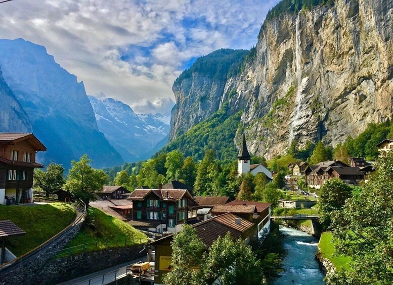 A mountainous village with houses, a church, and a river. 1