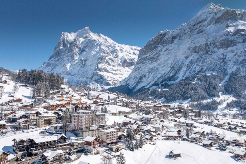A snow-covered mountain town with buildings and a prominent peak in the background. 4