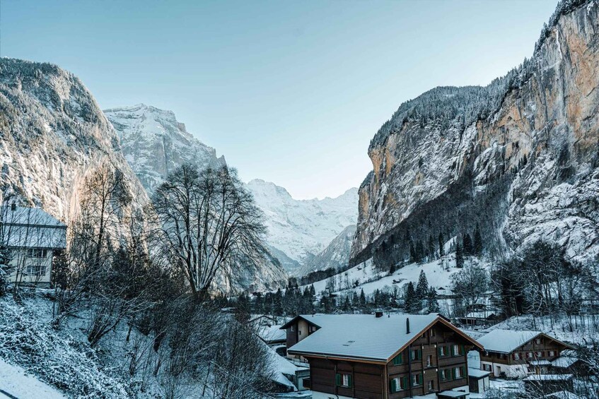 A snow-covered mountain village with wooden houses and a valley. 3