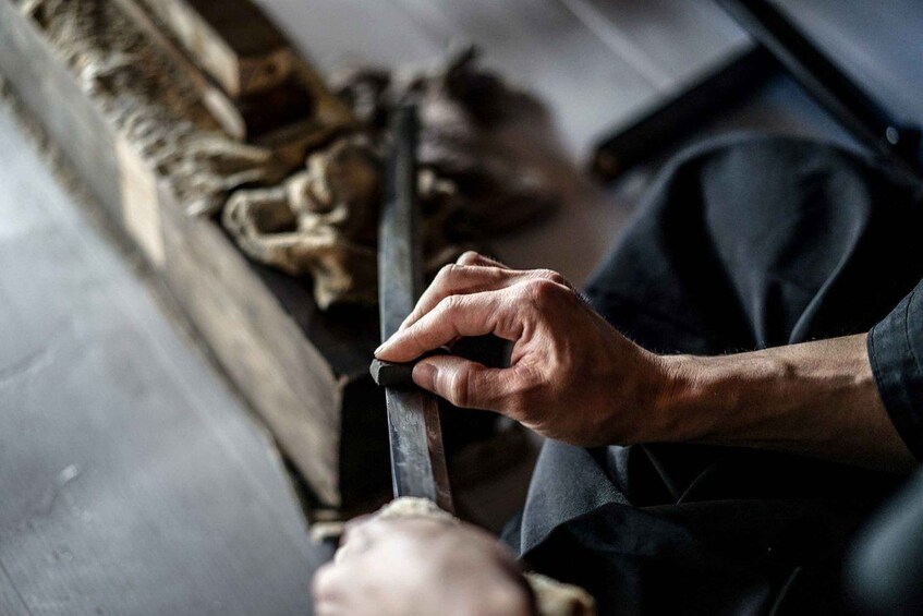 A person holding a tool, possibly a knife, near a wooden surface. 4