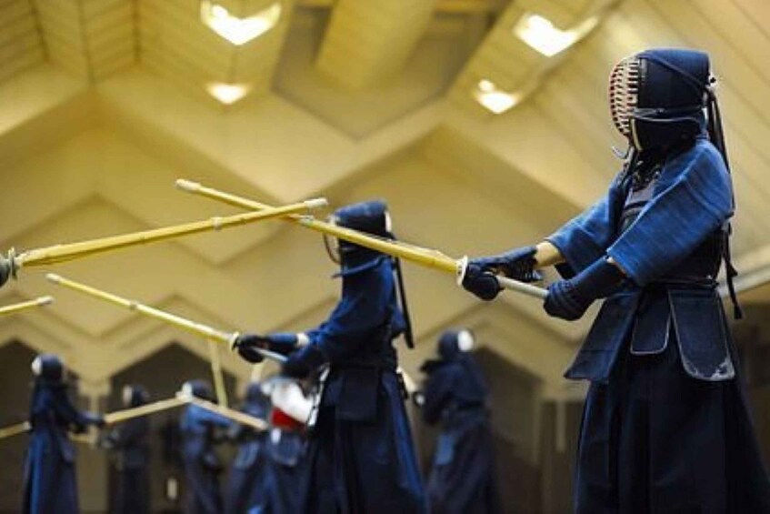A group of people in traditional martial arts attire holding wooden staffs. 5