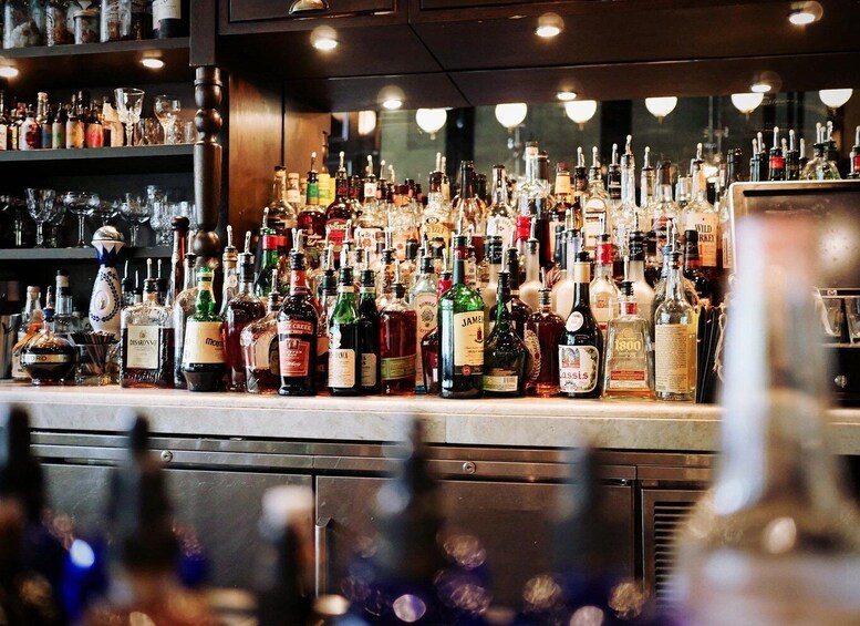 A bar counter with various bottles of alcohol and glasses. 4