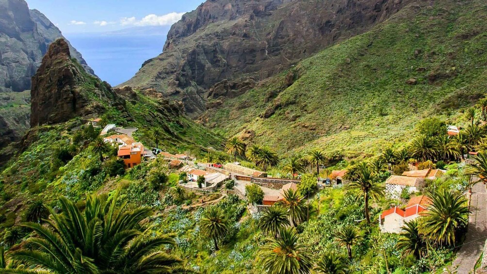 A mountainous landscape with a village nestled among lush greenery and rocky cliffs. 1