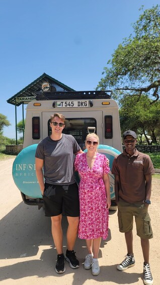 Three people standing in front of a safari vehicle with a sign that reads "TARANGI". 3