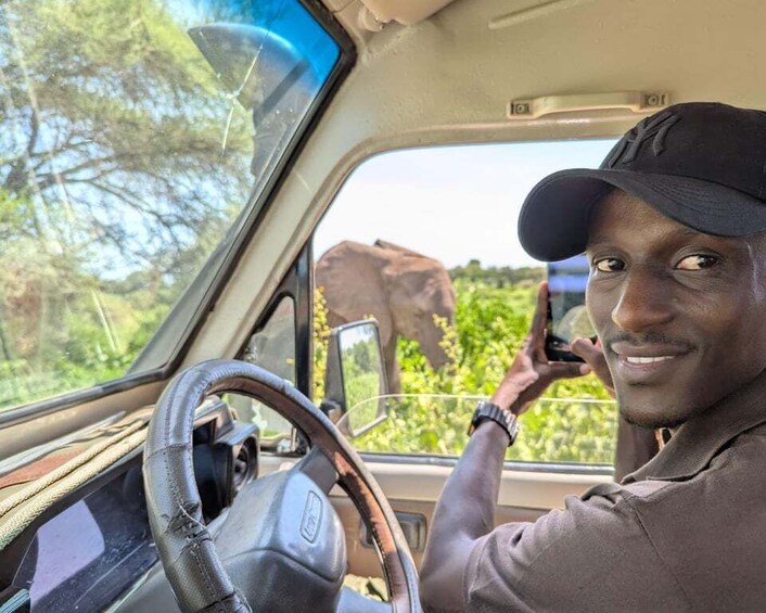 A person in a vehicle with a steering wheel, holding a smartphone, and looking out of the window. 5
