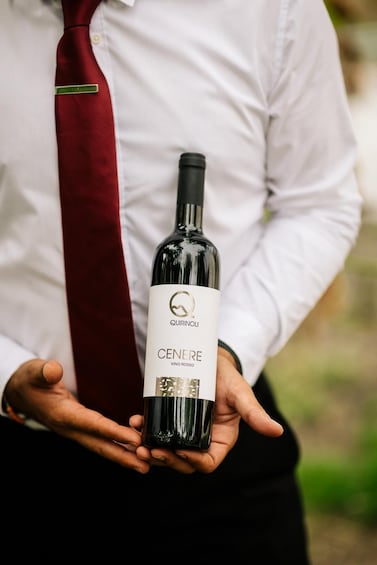 A person holding a bottle of wine with a label that reads 'CENERE VINO ROSSO.' 5