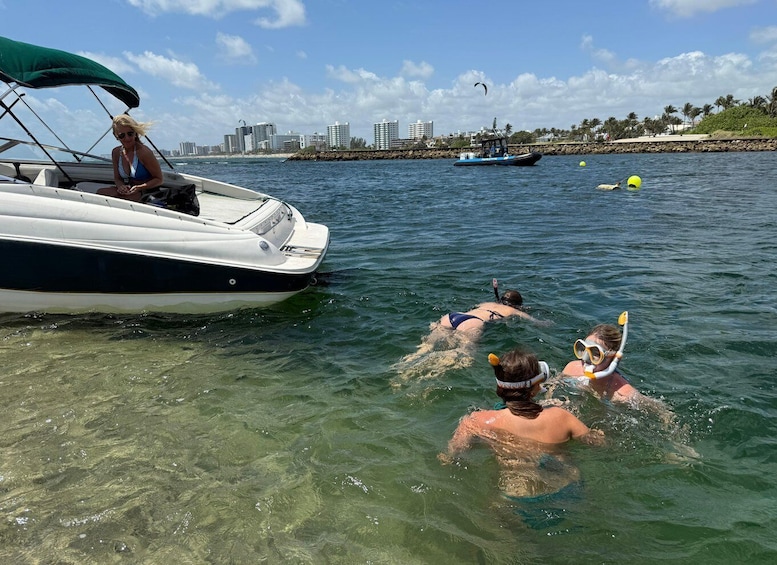 A boat with people snorkeling in the water, a city skyline in the background, and a clear blue sky. 5