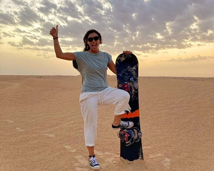 Une personne se tient sur une plage de sable et tient une planche de snowboard. 2