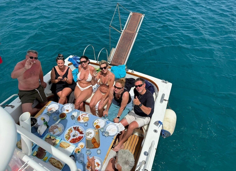 A group of people on a boat with a table full of food and drinks. 1