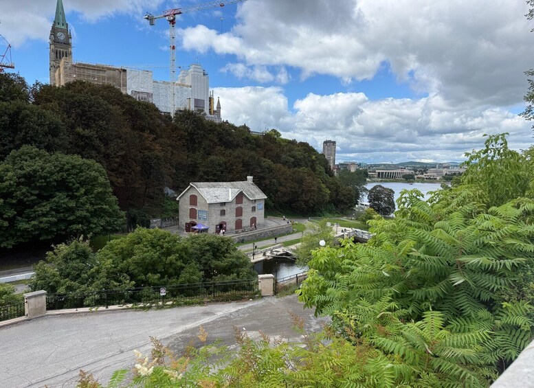 A historic building surrounded by lush greenery, a river, and modern high-rises in the background. 3