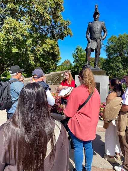 A group of people gathered around a statue in a park with trees in the background. 1