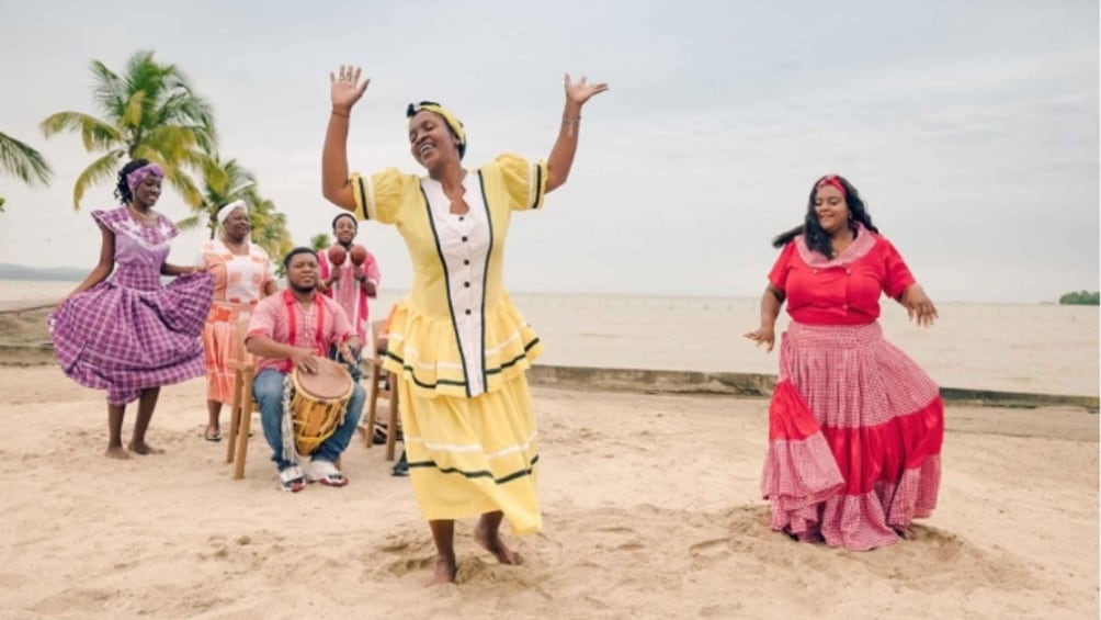 A group of people dancing on a sandy beach with palm trees in the background. 3