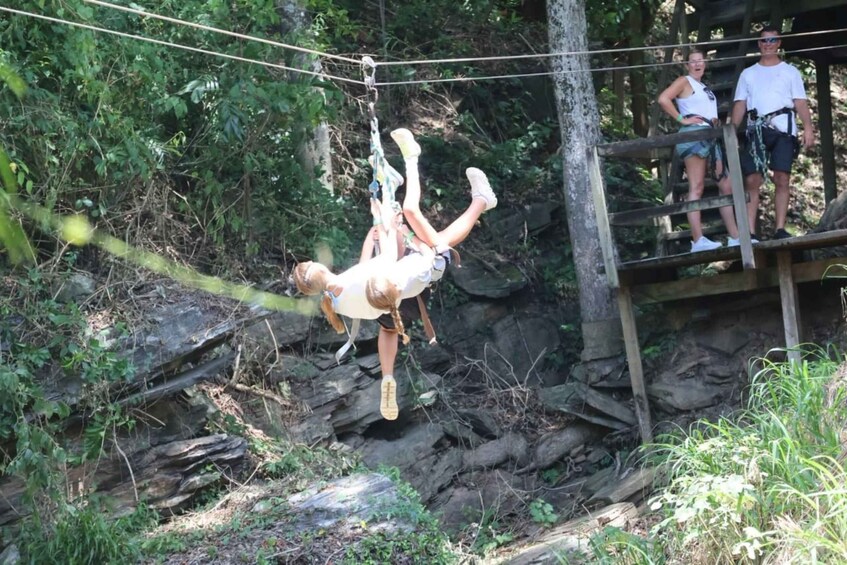 A person performing an acrobatic flip on a rope bridge in a forested area. 5