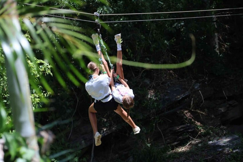 A person suspended in mid-air by a zip line in a forested area. 4