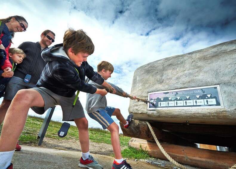 A group of people pulling a large stone with a rope. 2