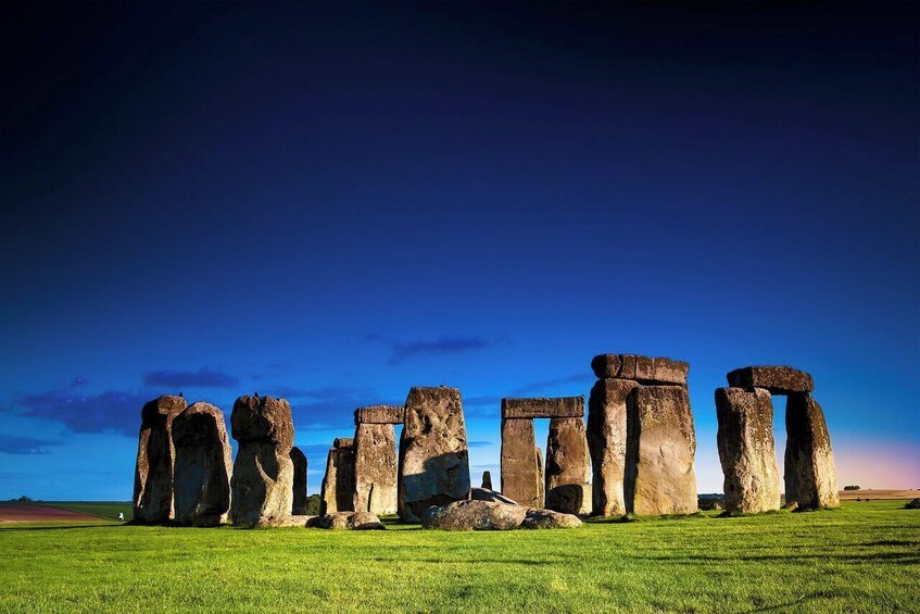 Stonehenge standing in a grassy field under a clear sky. 1