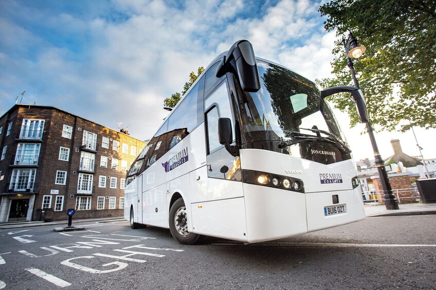 A white tour bus with 'Premium Coaches' branding parked on a street. 4