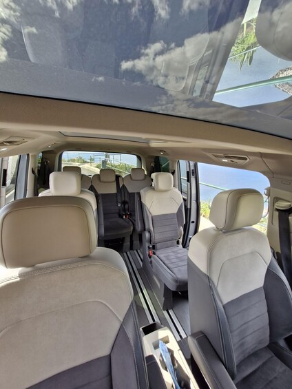 The interior of a vehicle with beige and black seats, a sunroof, and a view of the outside. 4