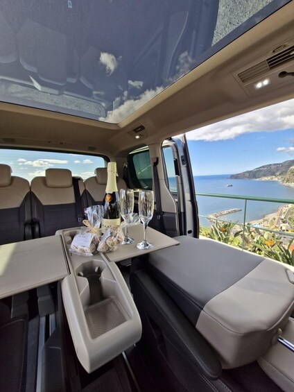 A car interior with a table set for two, a bottle of wine, and snacks. 2