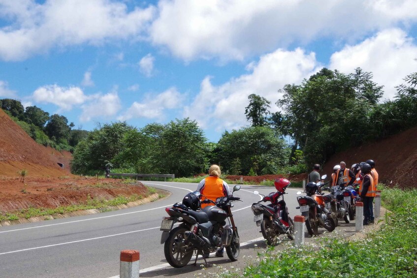 A group of motorcyclists wearing safety gear on a winding road surrounded by greenery. 3