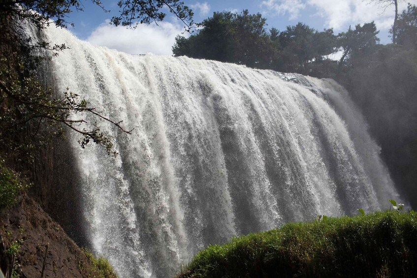 A large waterfall cascading down a rocky cliff surrounded by greenery. 5
