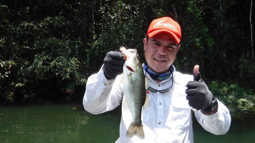 A person holding a fish and giving a thumbs up. 2